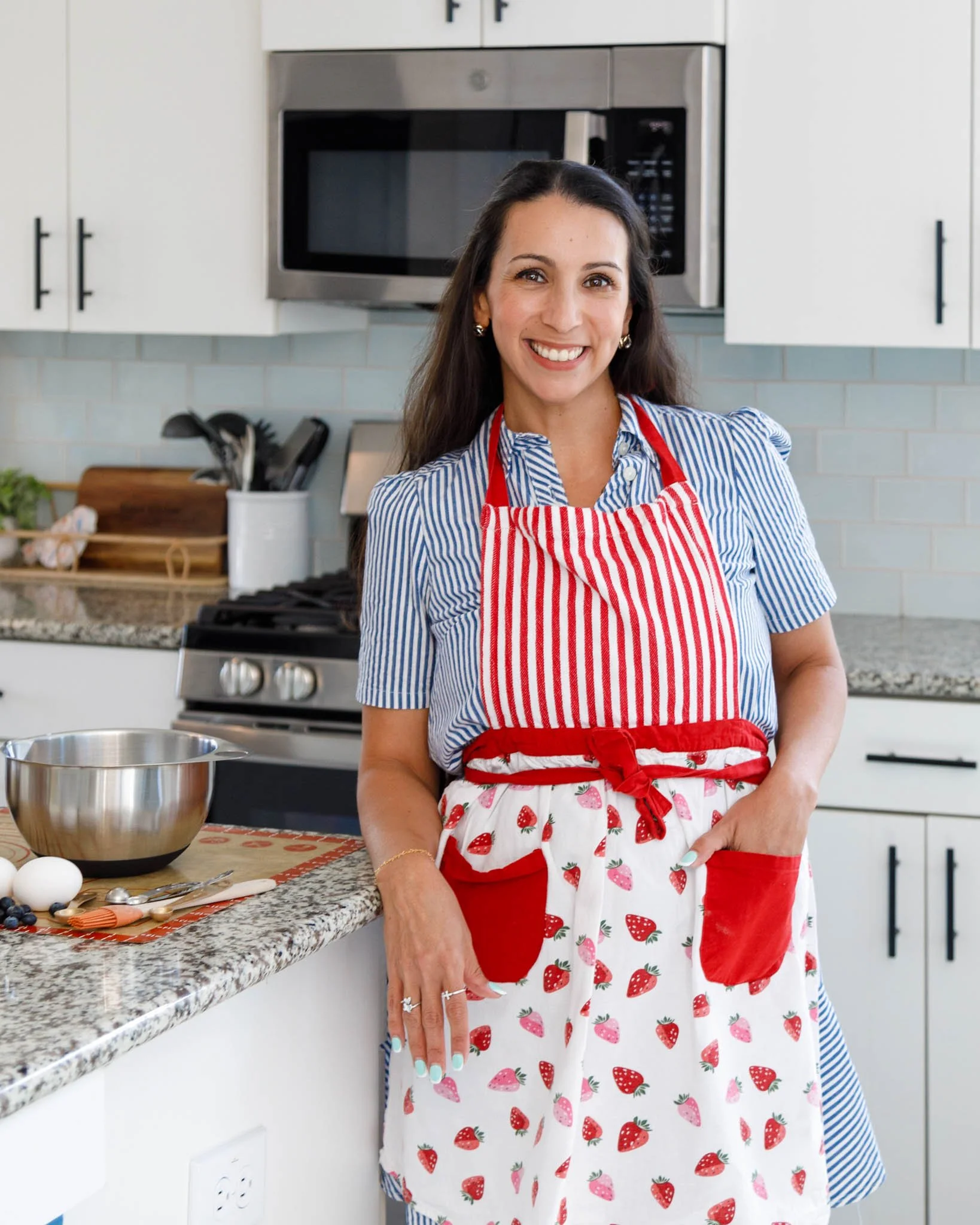 branding photo of woman smiling leaning against kitchen counter with baking apron and supplies / Photo by Erin Valkner Photography of New Braunfels, Texas. See more at www.erinvalknerphotography.com/blog