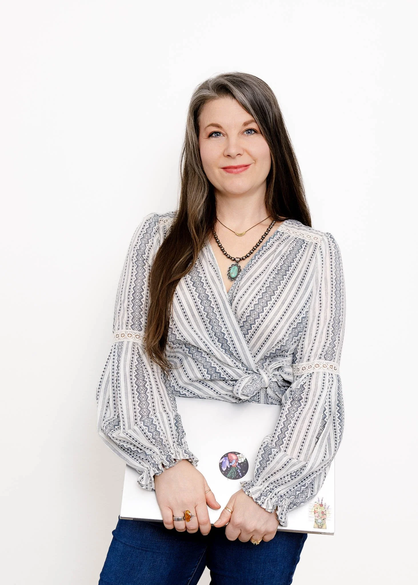 branding photo of woman with long dark hair holding laptop standing pose on white background in studio / Photo by Erin Valkner Photography of New Braunfels, Texas. See more at www.erinvalknerphotography.com/blog
