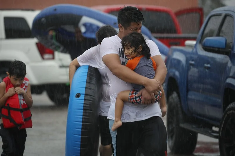 Mario Qua holds Wilson Qua as they evacuate their flooded home after the area was inundated with flooding from Hurricane Harvey on August 27, 2017 in Houston, Texas. (Photo by Joe Raedle/Getty Images) From the Palm Beach Post.