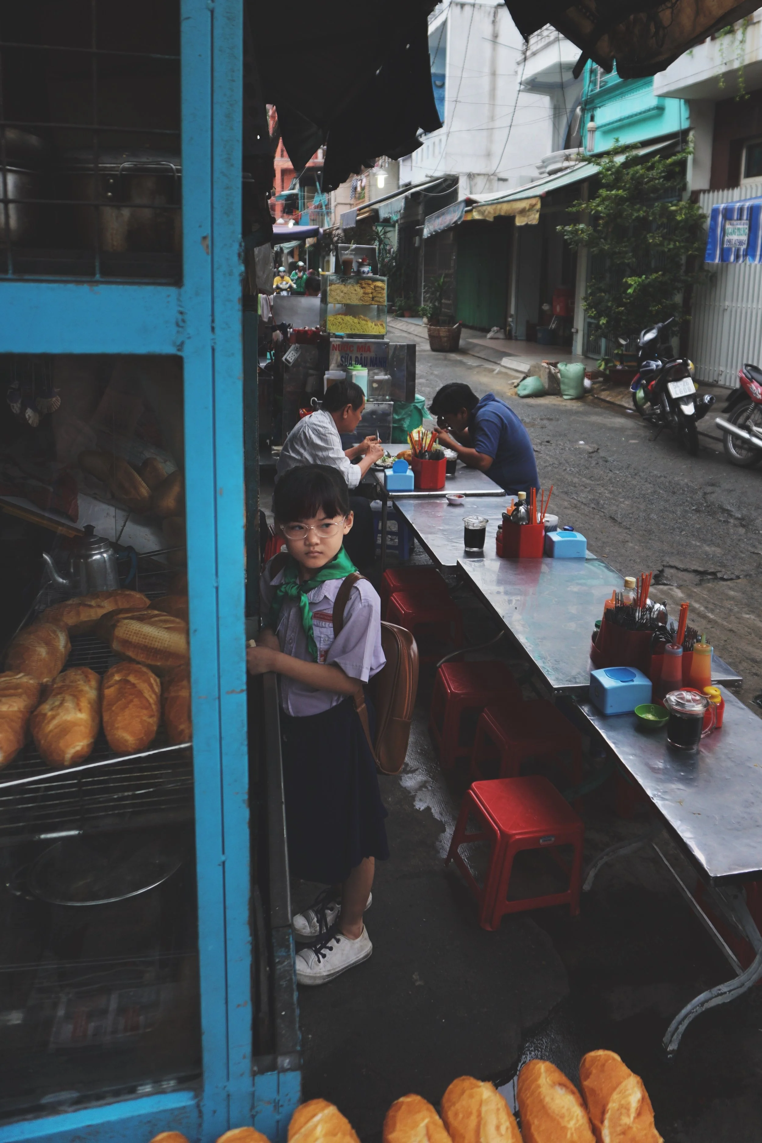 A little girl takes herself to school. But first, banh mi.