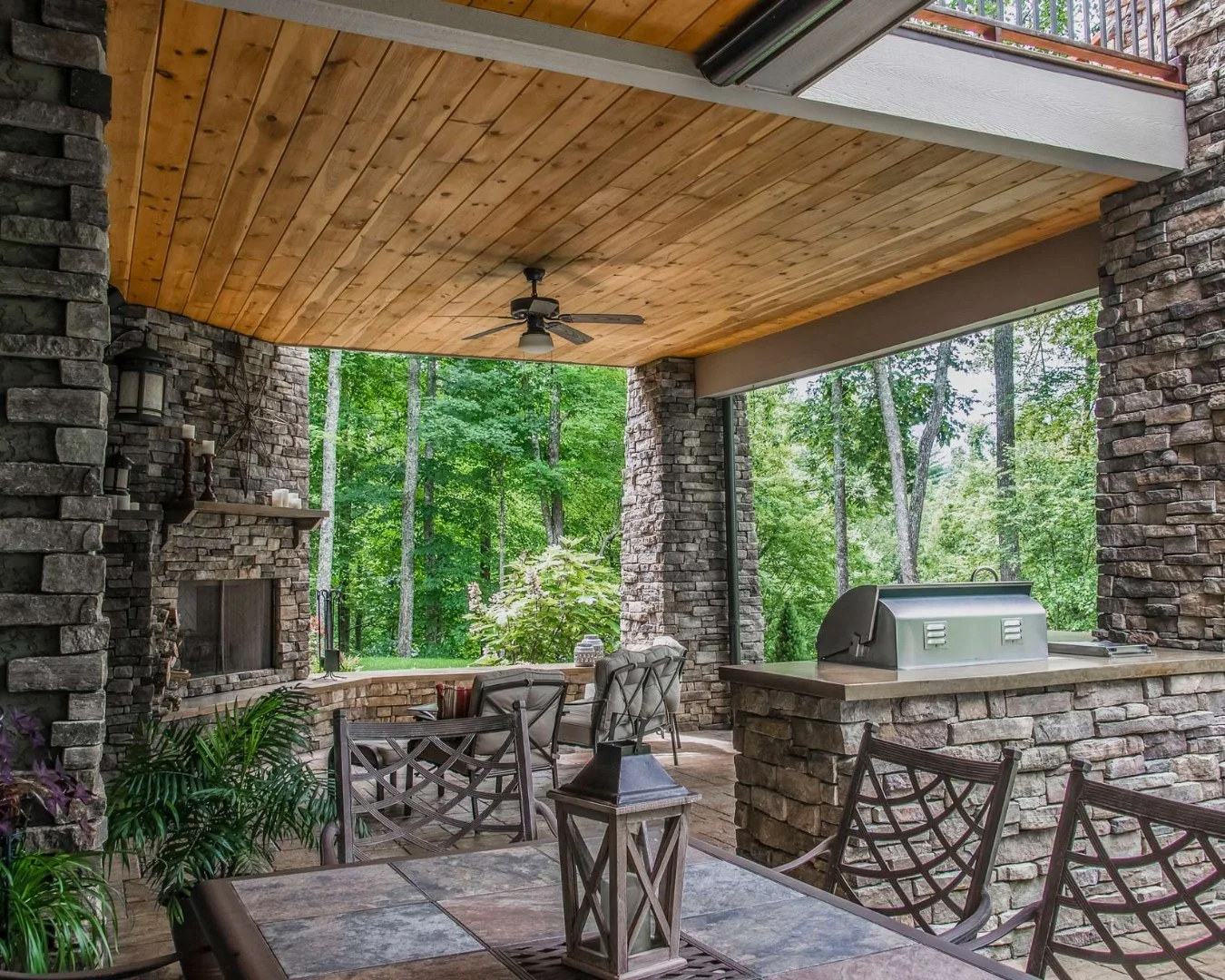 Rain or shine, this outdoor kitchen is ready.⁠
⁠
This fully outfitted outdoor kitchen features a built-in cooking center, refrigerator, sink, stone benches, and a corner fireplace. ⁠
⁠
Our team engineered a specialized dry-in system, finished with a 