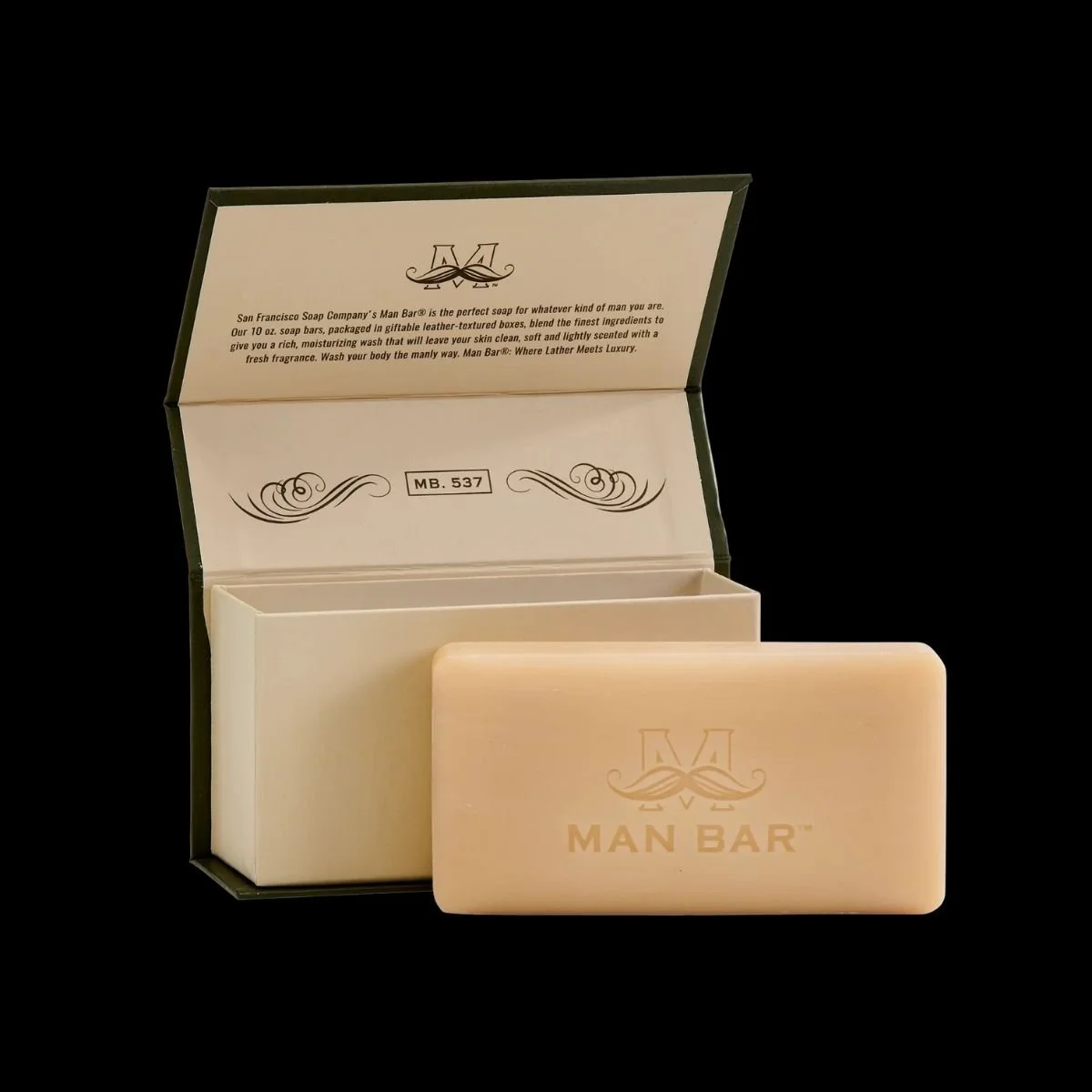 Man Bar Soap MB.537 Exfoliating Cardamom and Juniper 10oz bar removed from open dark brown leather-textured gift box, showing embossed Man Bar logo on cream-colored soap