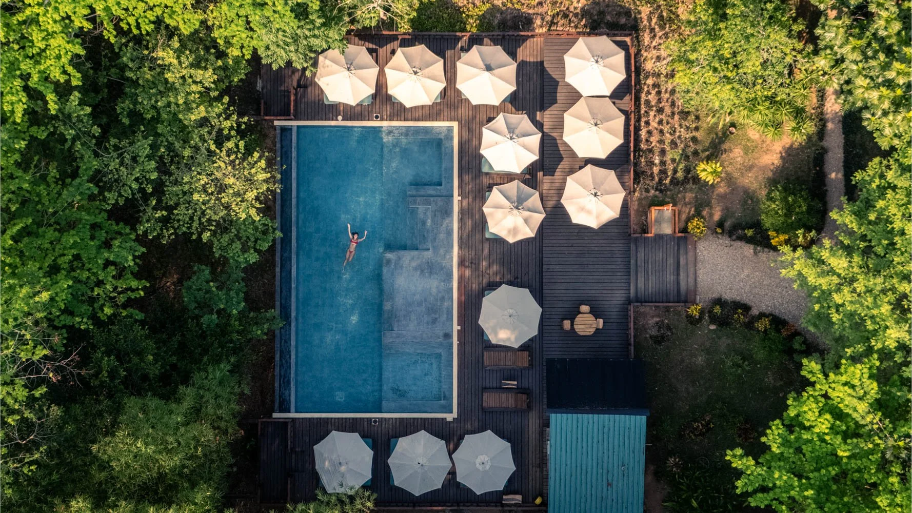 woman floating on back in infinity pool surrounded by nature in Belize at Sweet Songs Jungle Lodge
