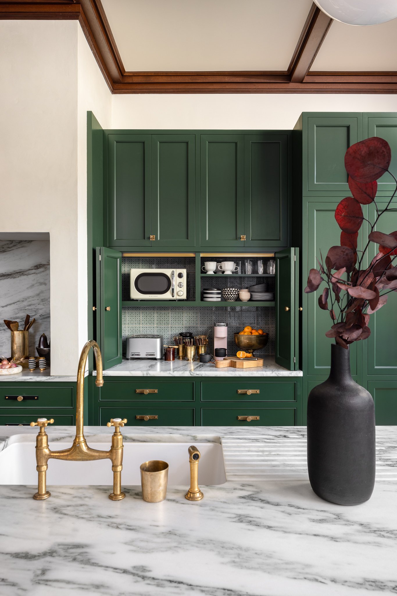 Marble countertop with integrated drainboard sink and aged brass bridge faucet in custom Philadelphia kitchen remodel
