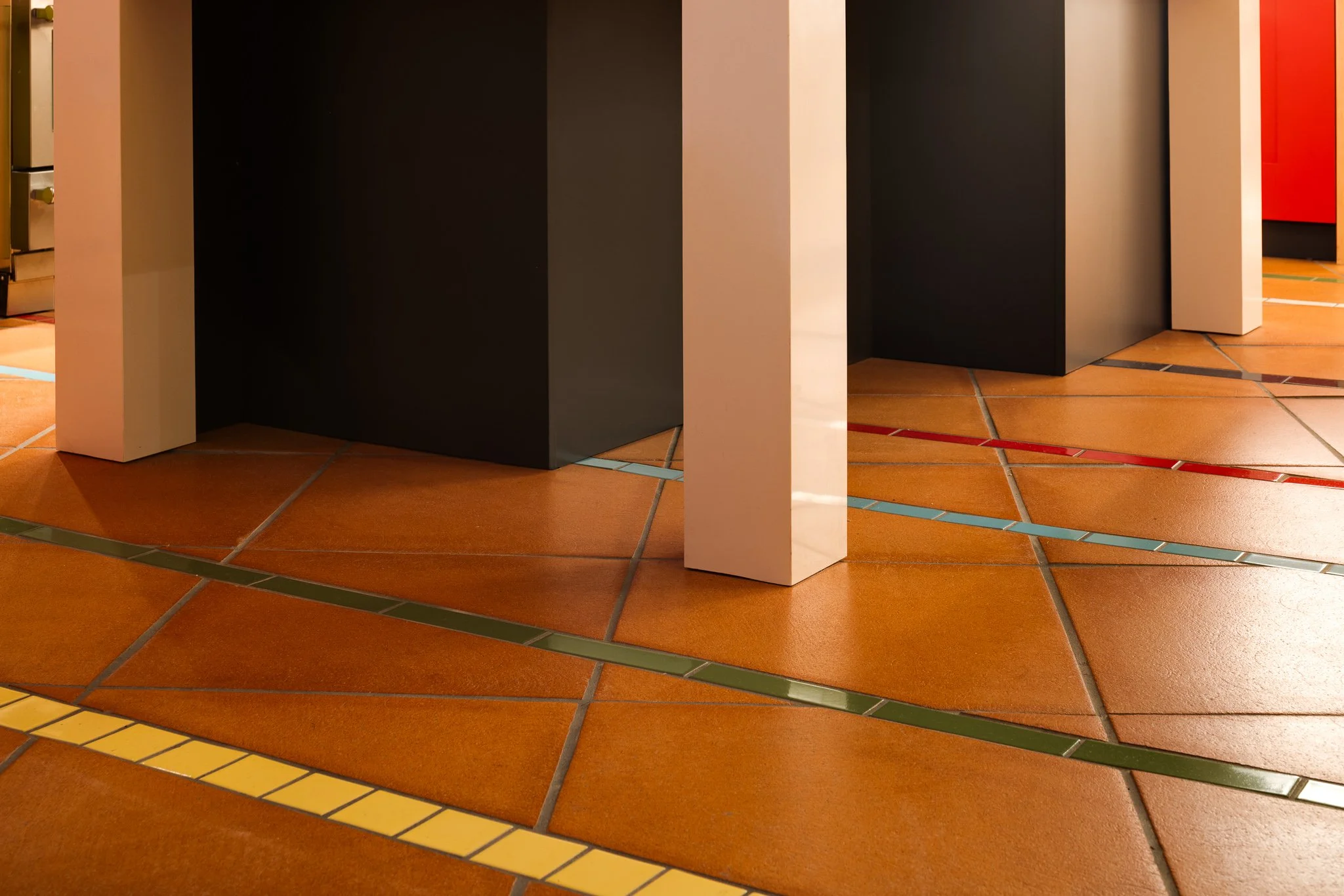 Terracotta floor tile with intersecting bands of colorful Fireclay tile.