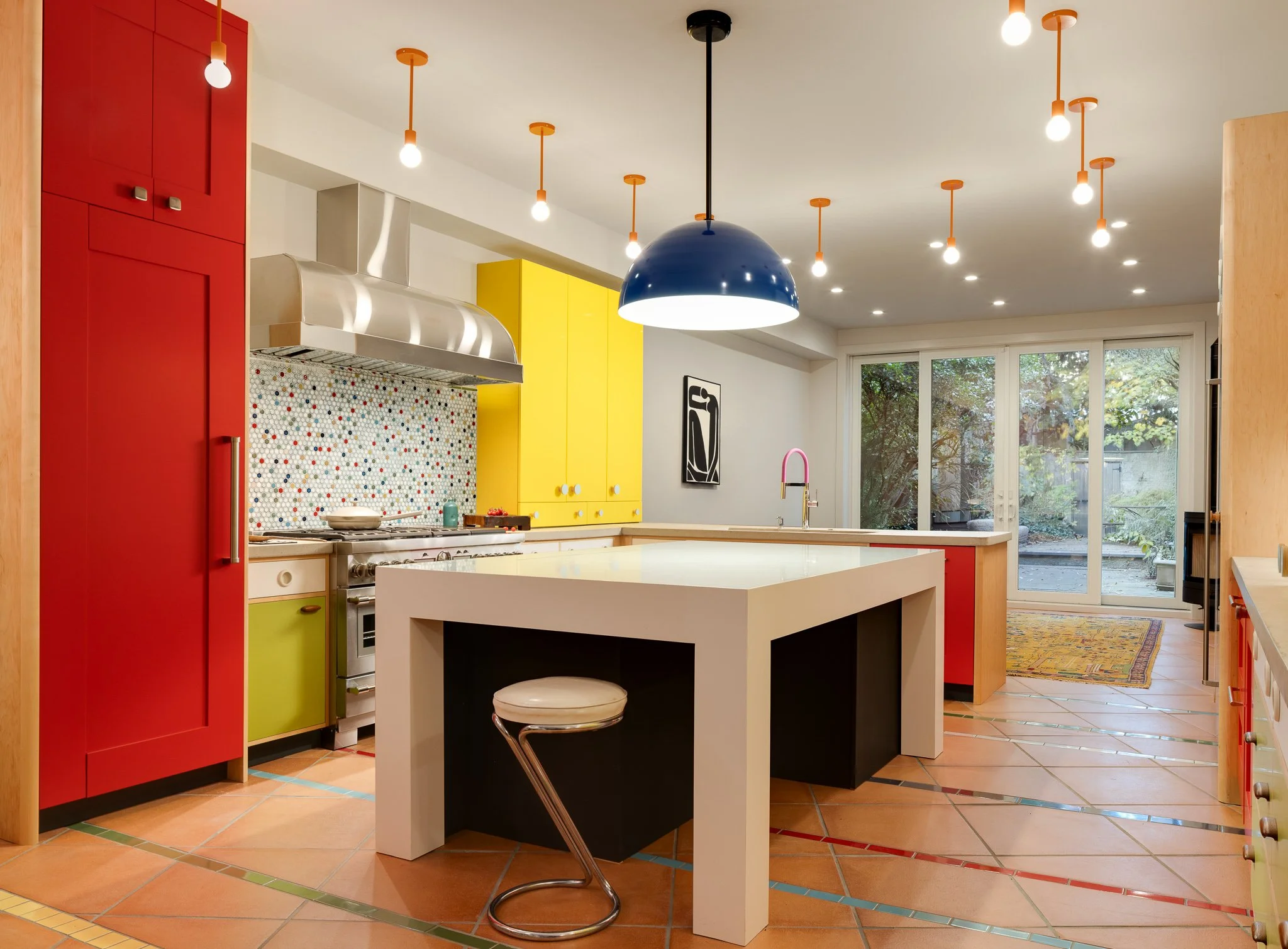 Wide view of the kitchen with colorful cabinetry, family room seating, and outdoor views designed by J.THOM Philadelphia.