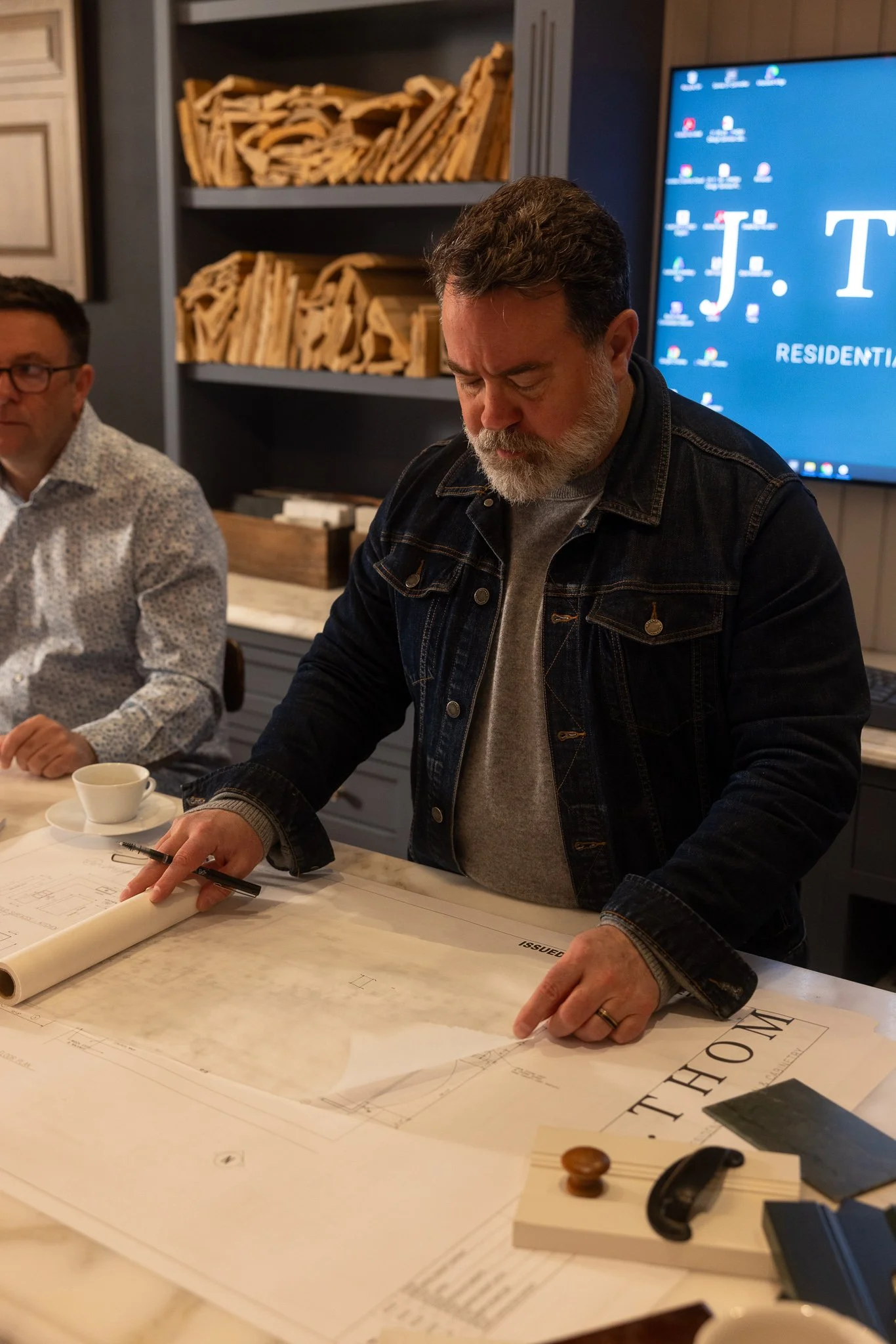 J.THOM founder Jason Thompson reviews architectural plans and cabinetry samples during a residential design consultation.