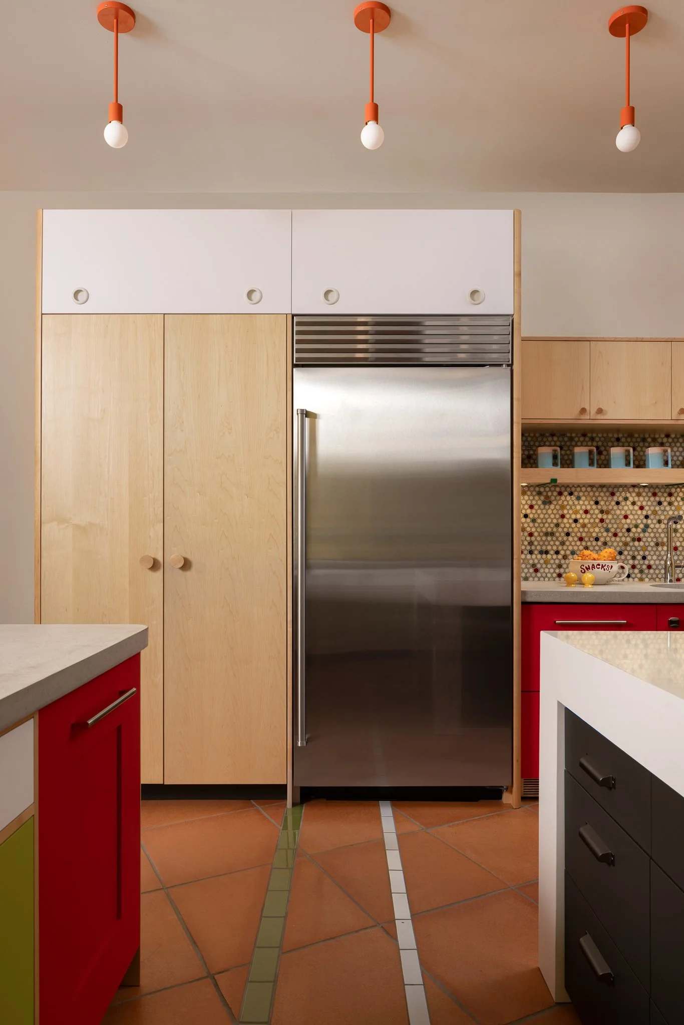 Custom-built maple pantry and cabinetry with integrated refrigeration, colorful finishes, and red dishwasher.