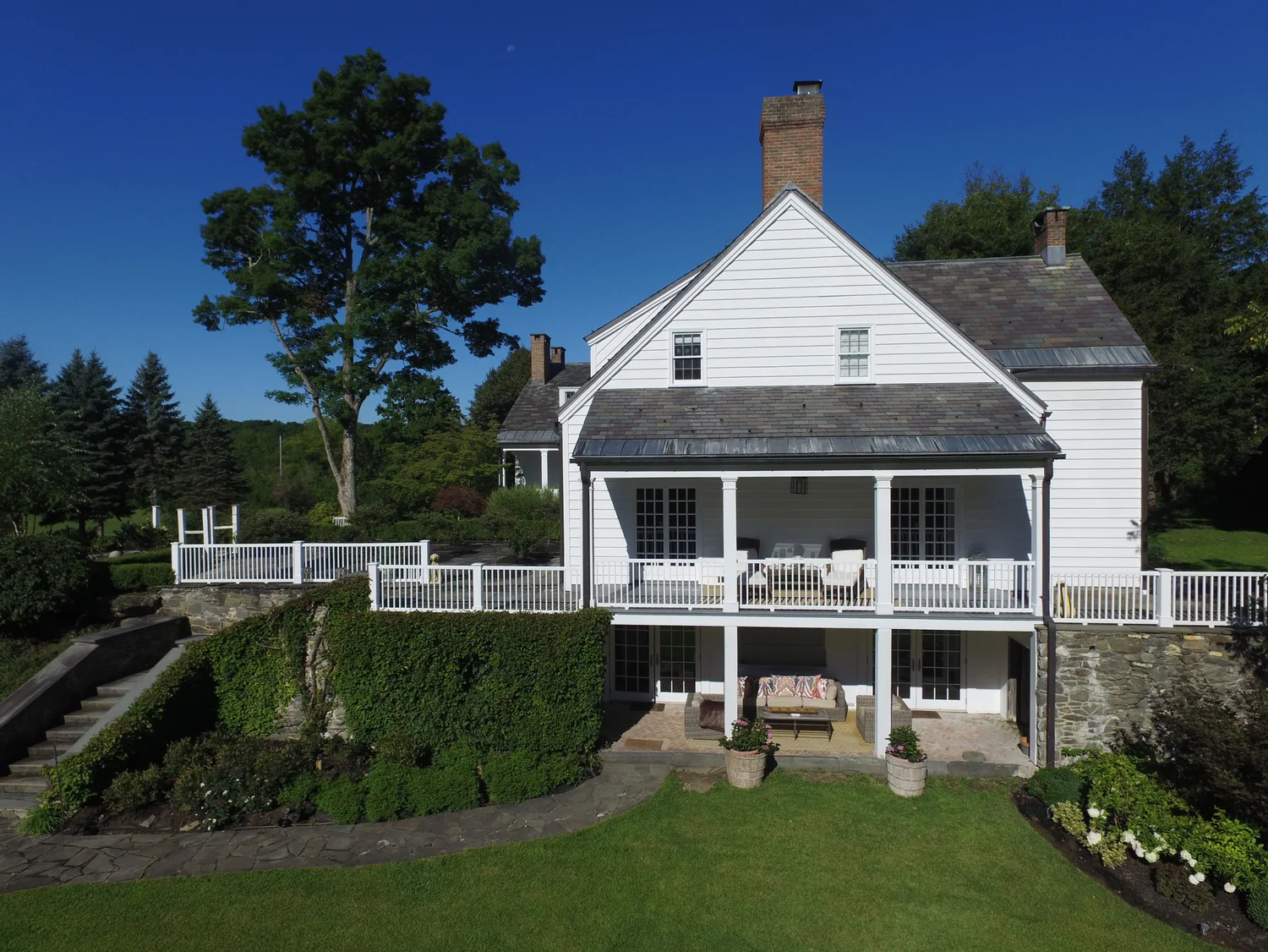 The historic white manor with its two-story porch and terraced gardens — the view that greets you at the top of the drive