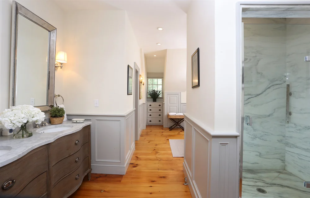 The marble primary bathroom with double vanity and walk-in shower