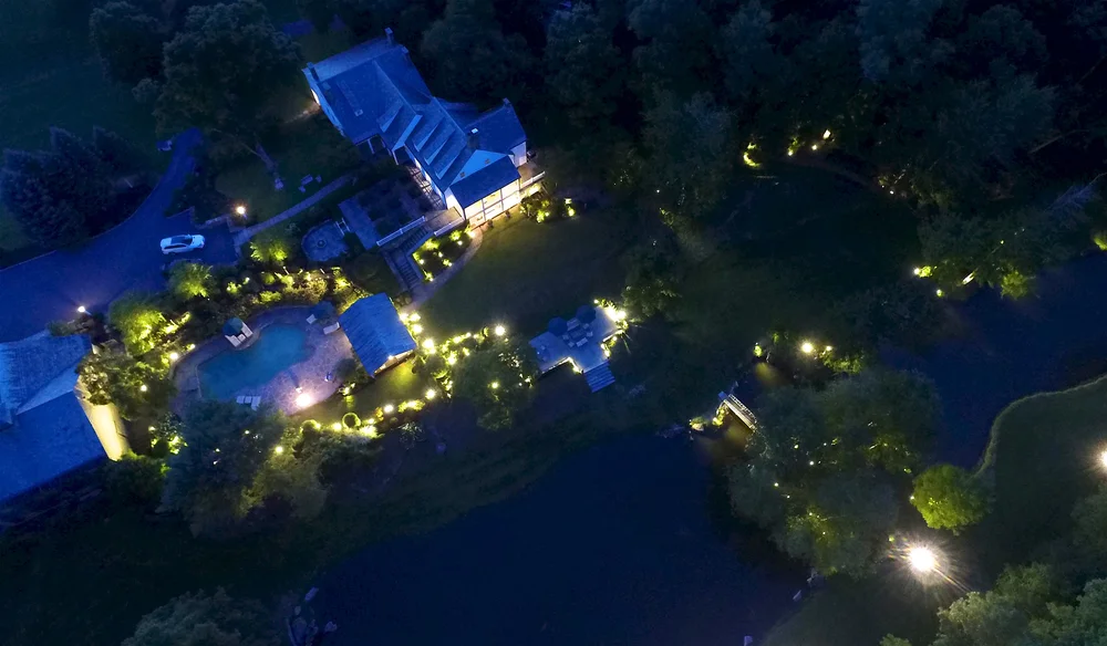 Night aerial of the estate with gardens and pool lit