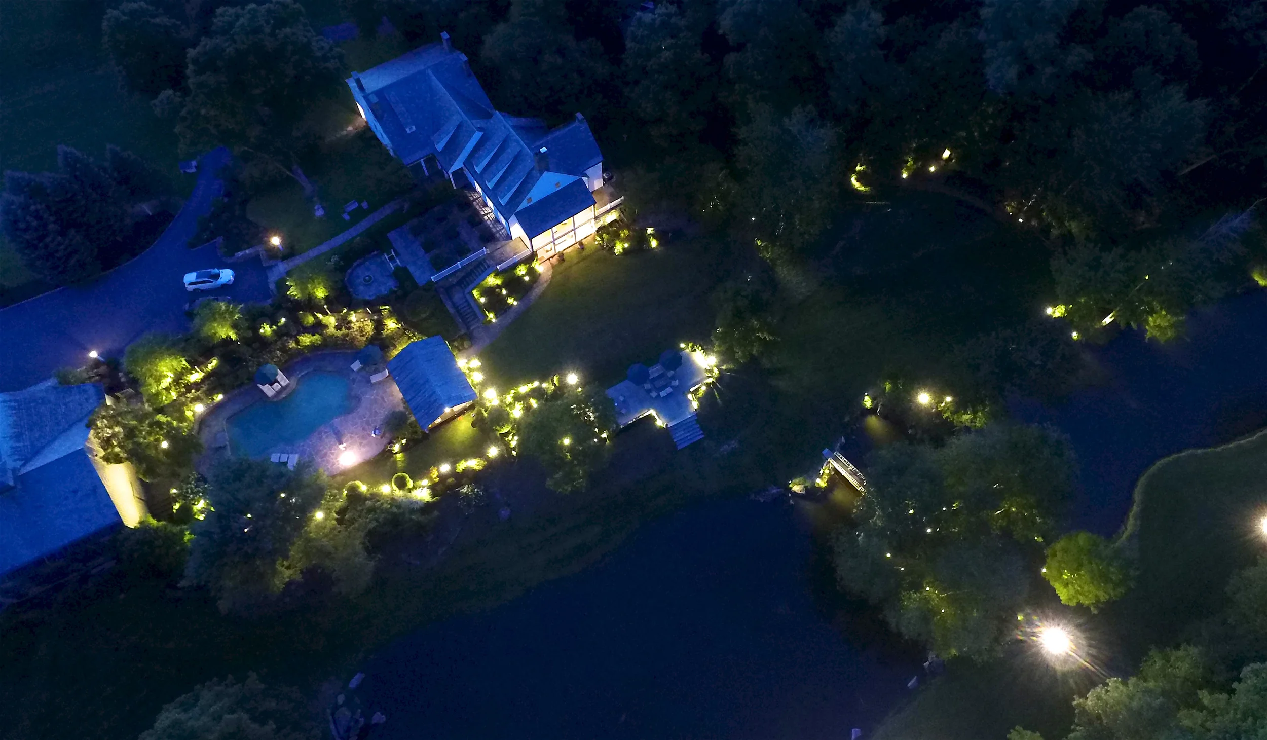 The Hendricks House estate lit up at night, pool and gardens glowing
