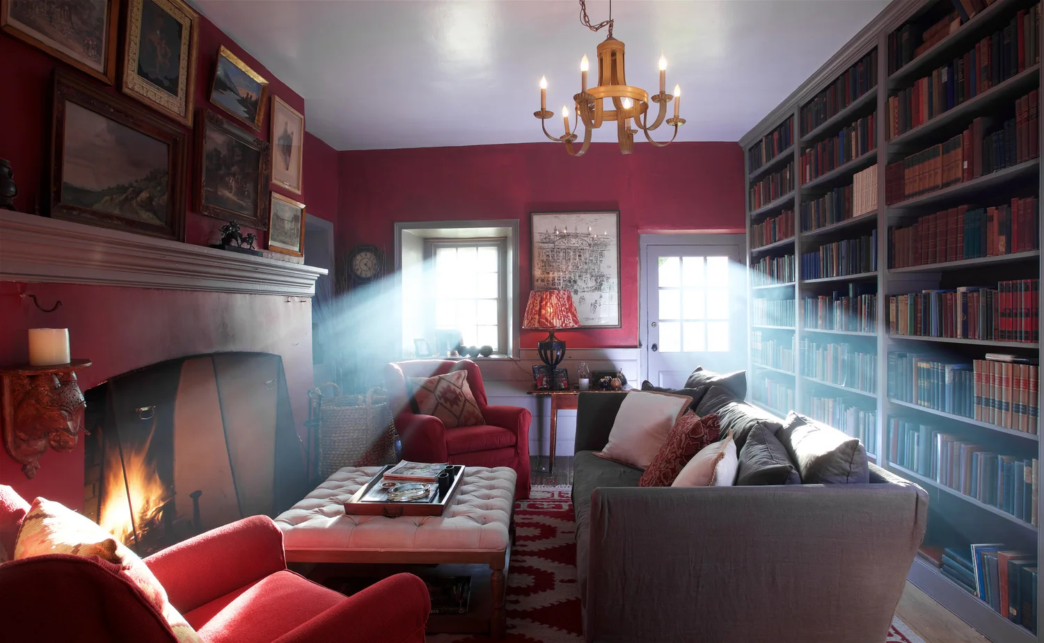 The crimson winter library with floor-to-ceiling antique books and a lit fireplace