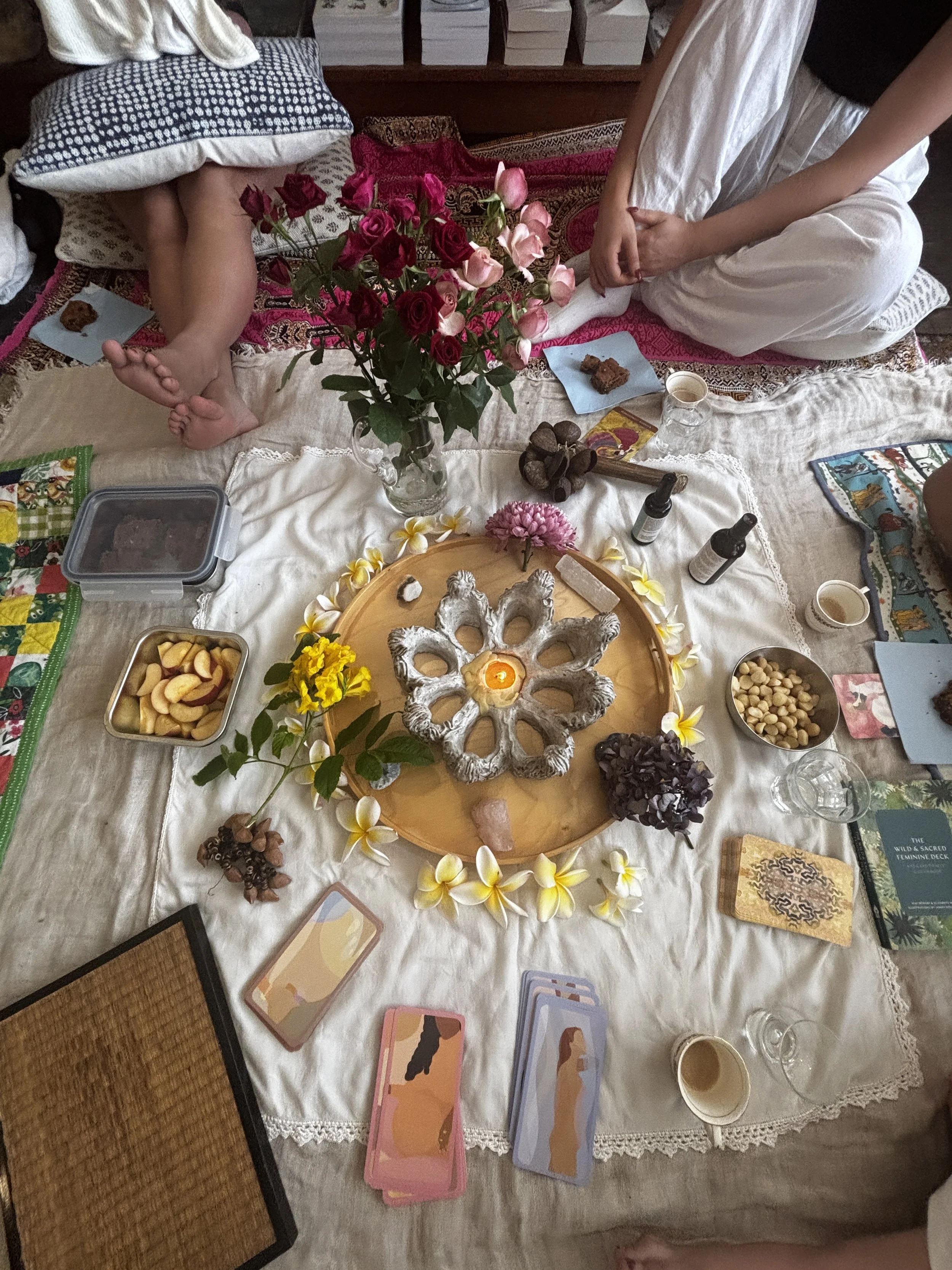Mothers' Circle gathering Sydney Eastern Suburbs, Coogee. A table set for a spiritual or meditative practice with tarot cards, candles, flowers, and various small containers and objects.