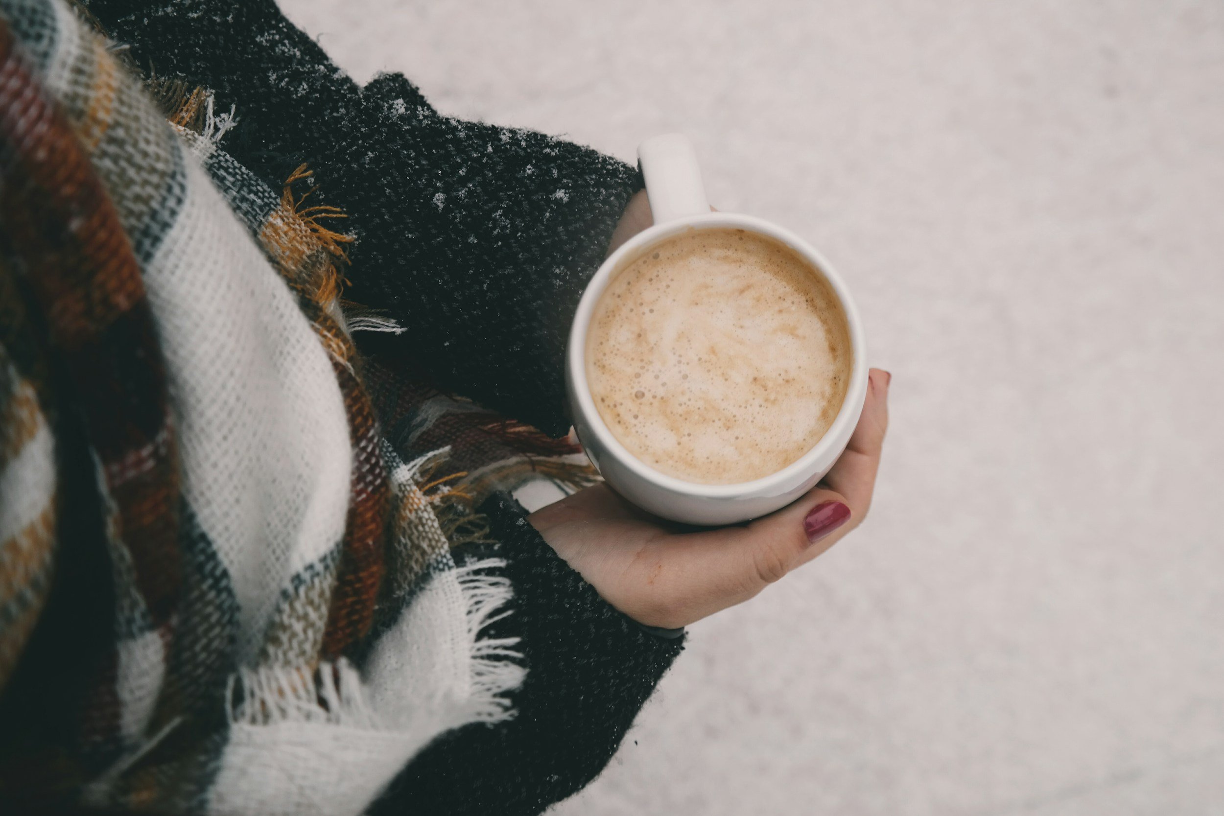A person holding a white mug filled with a warm drink - part of the care you recieve with Pink Flamingo Postpartum doula provide home visit care in a Postpartum Care Package.