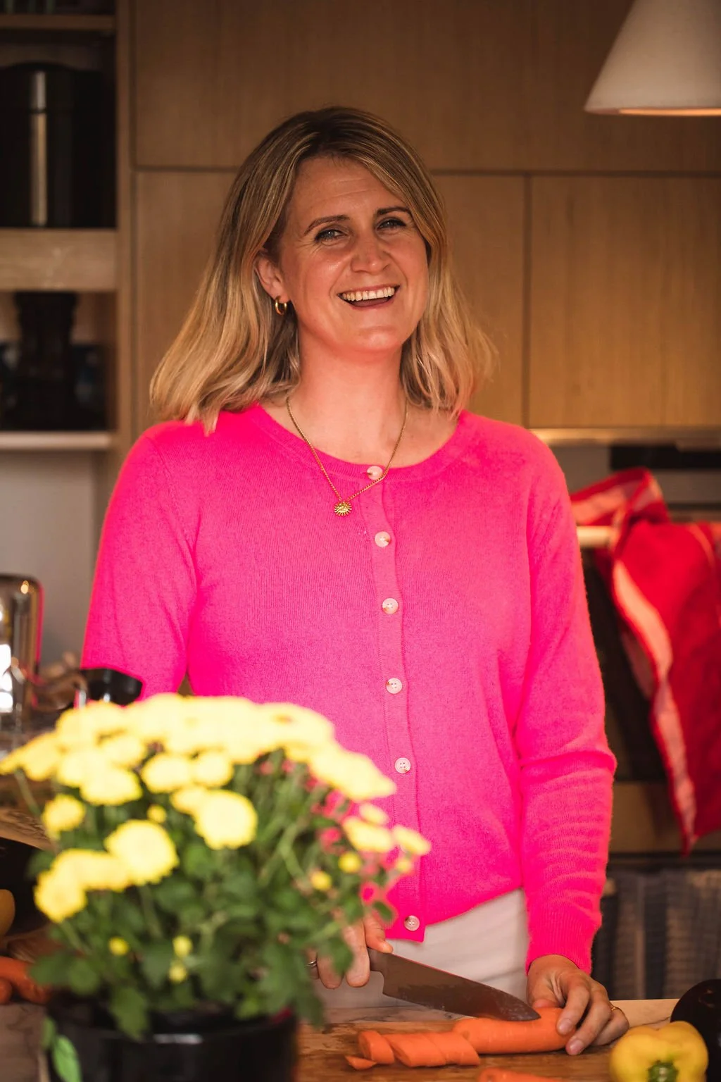 Hats, preparing fresh vegetables in her home kitchen, reflecting her holistic approach to supporting women through pregnancy, postpartum, education, nourishment and healing.