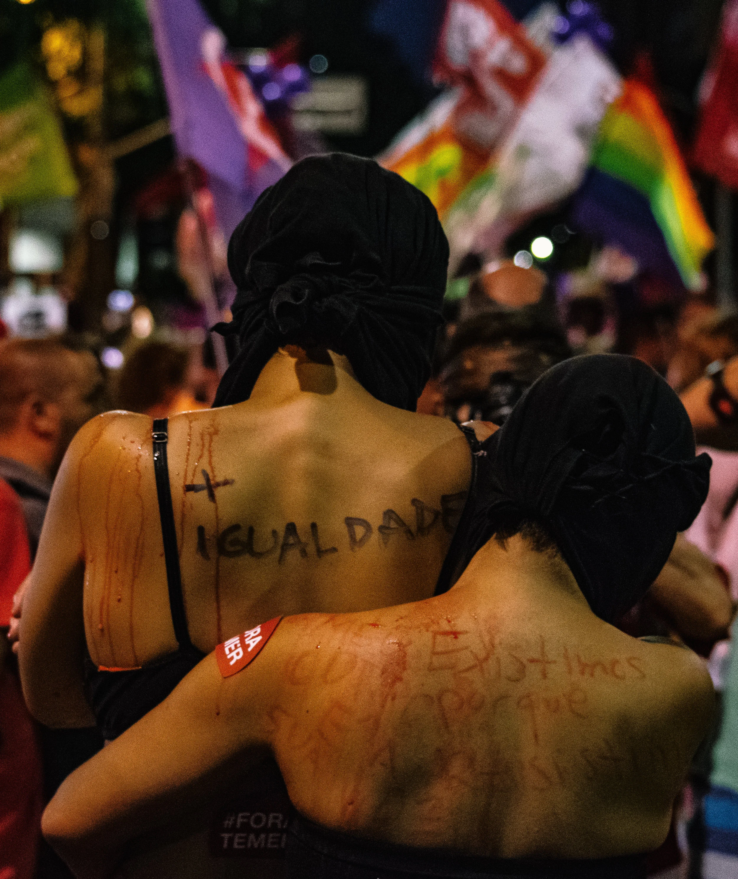 Performing artists in Rio embrace during a march for women's rights. Igualdade (equality) is written on the exposed back of one of the protesters.
