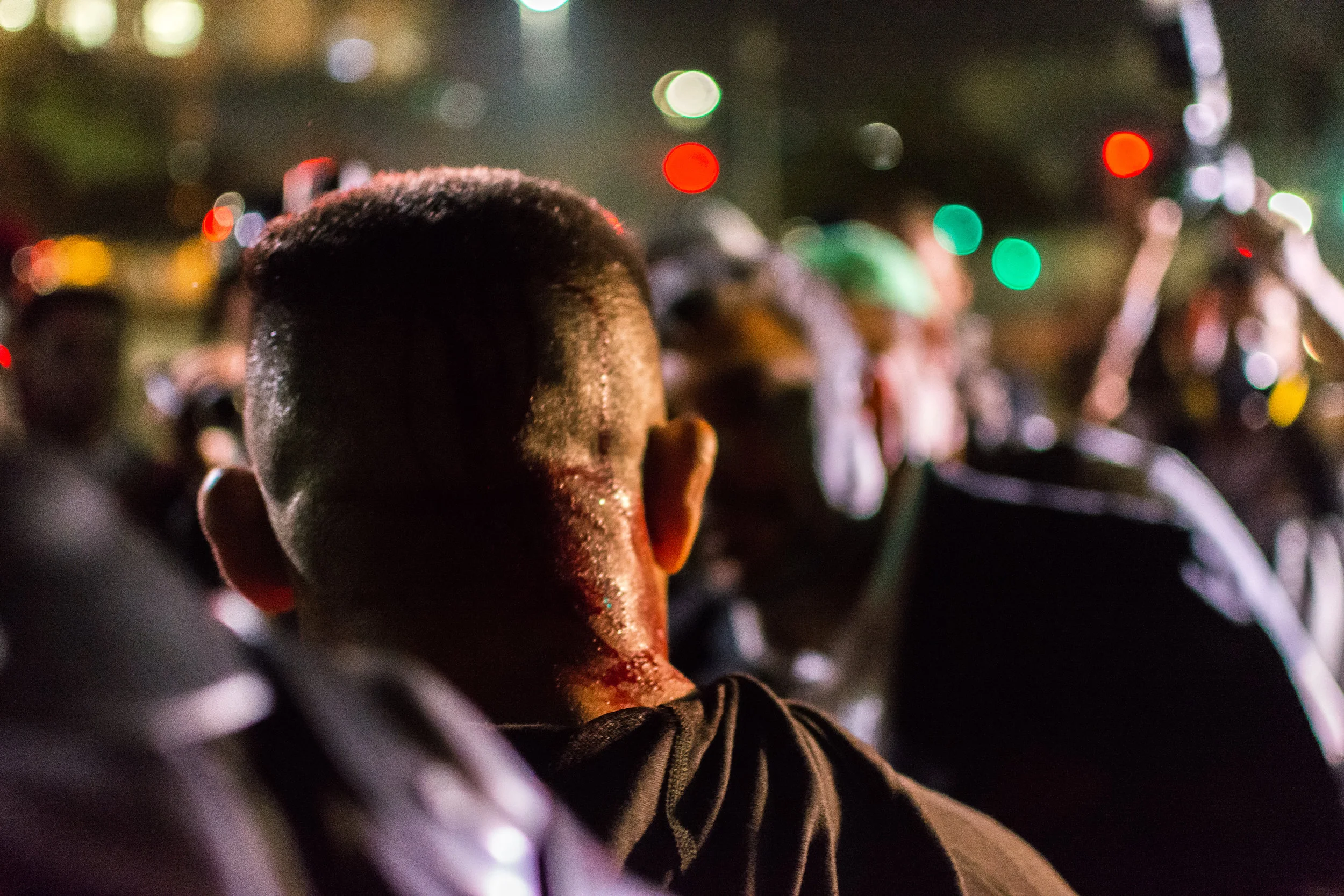 An undercover police officer is confronted by a lawyer after taking a camera from a journalist seemingly without cause. The officer was injured by protesters when his identity was discovered.