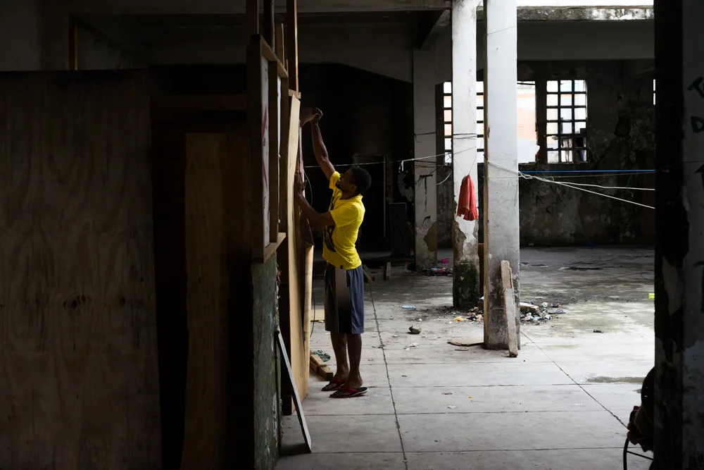 A resident of the former Ministry of the Economy building takes apart the wooden boards that used to make up the walls to his ad hoc apartment. (Photo: C.H. Gardiner)