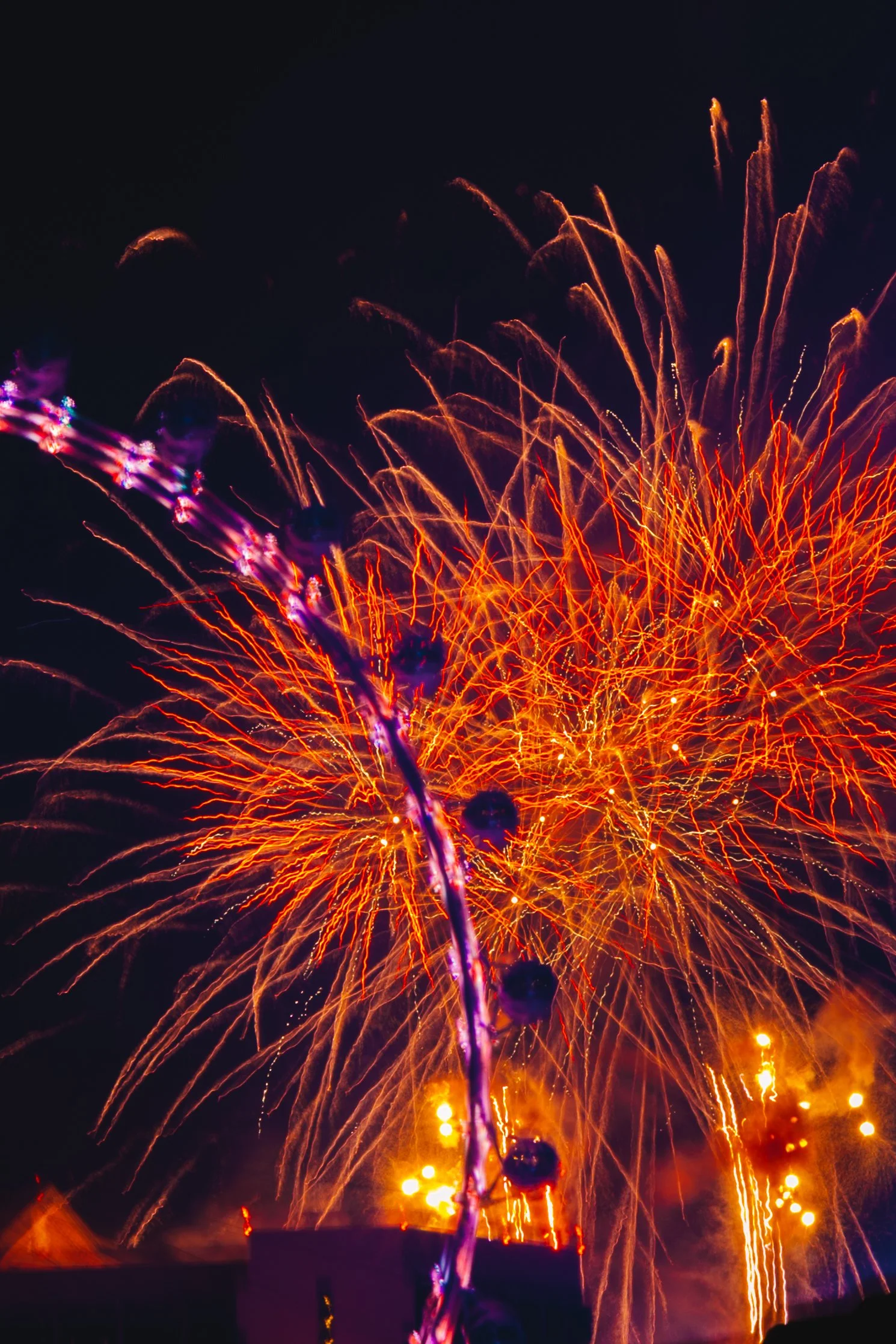 Colorful fireworks display in the night sky with bright streaks of orange, yellow, and purple lights.