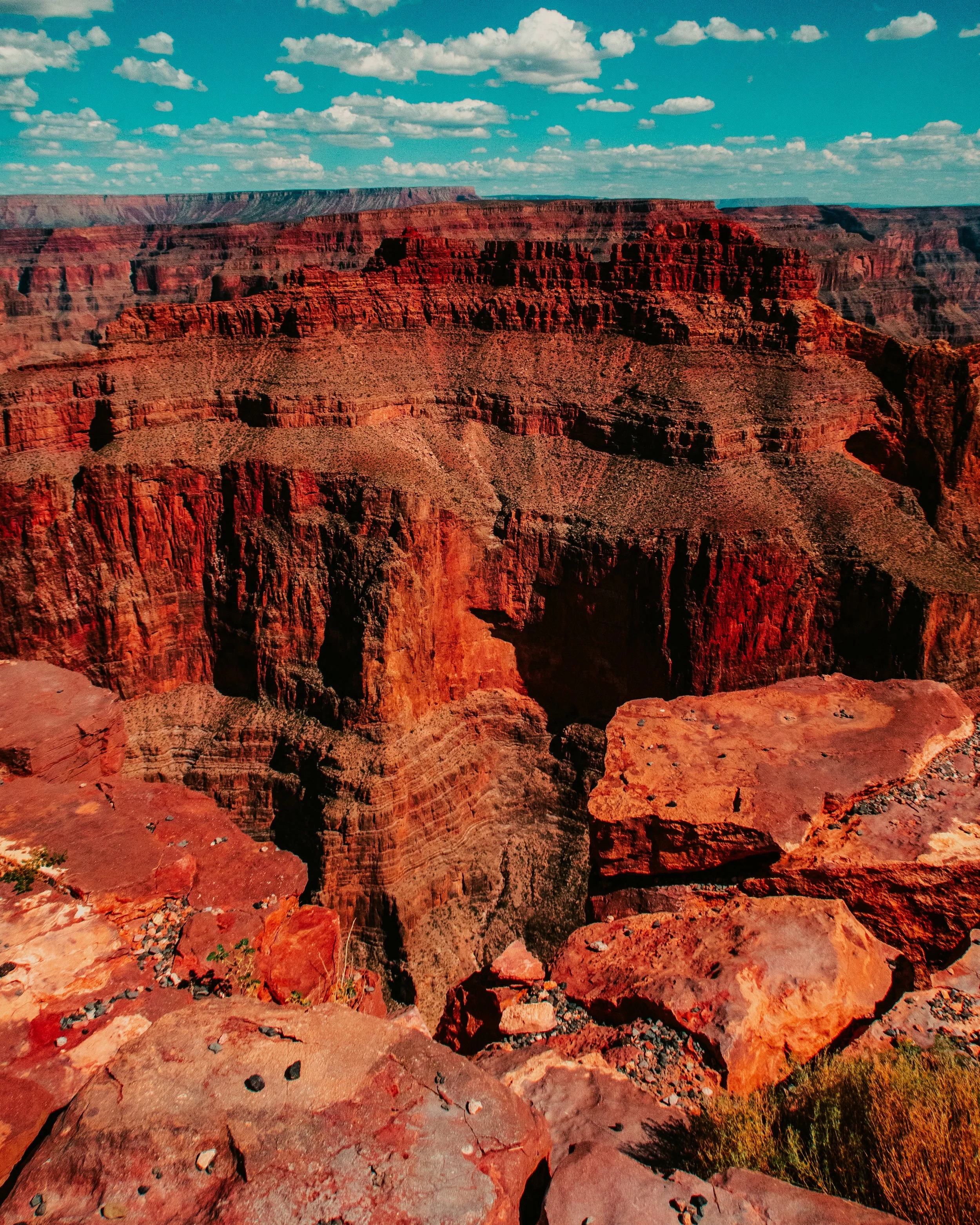 View of the Grand Canyon showcasing red rock formations, cliffs, and layered canyon walls under a partly cloudy sky.