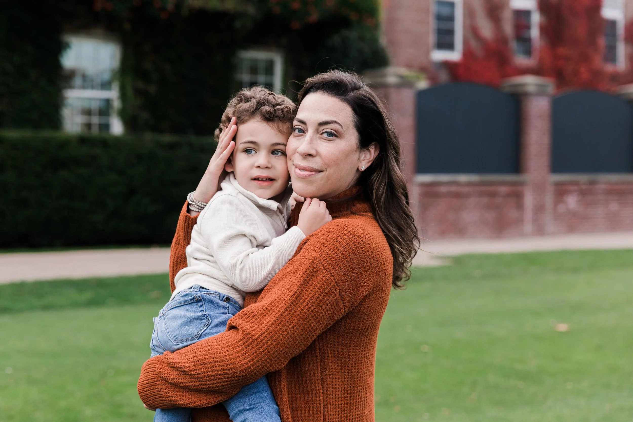 A mom holds her young boy and gently presses their cheeks together. They calmly look at the camera.