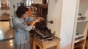 Using a hand-press to squeeze out the moisture from the couched paper and felt layers