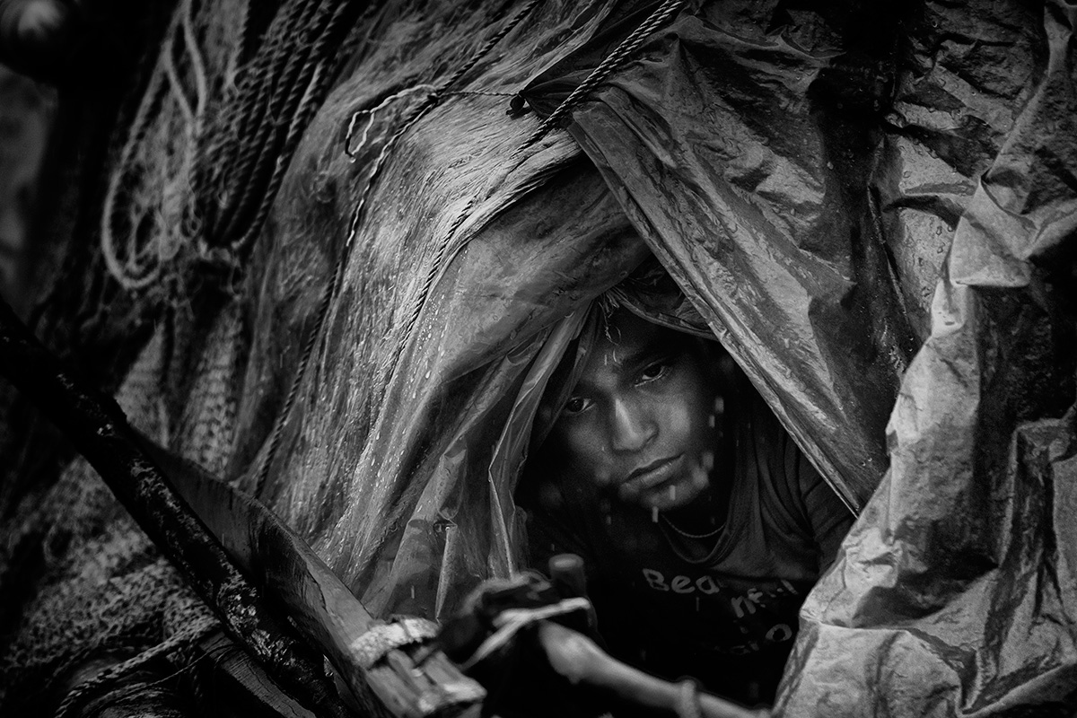 A son of a hilsa fisherman huddles inside a boat away from the rain, waiting for his father to return. Pirates had kidnapped him and held him for nine days. Did he have a chance to escape? “I was on a boat, where would I escape to? No, it is best to wait out these kidnappings.” They fed him once in two days, he said. On the appointed day, he was returned to his parents for 20,000 Taka (about $255) in ransom.