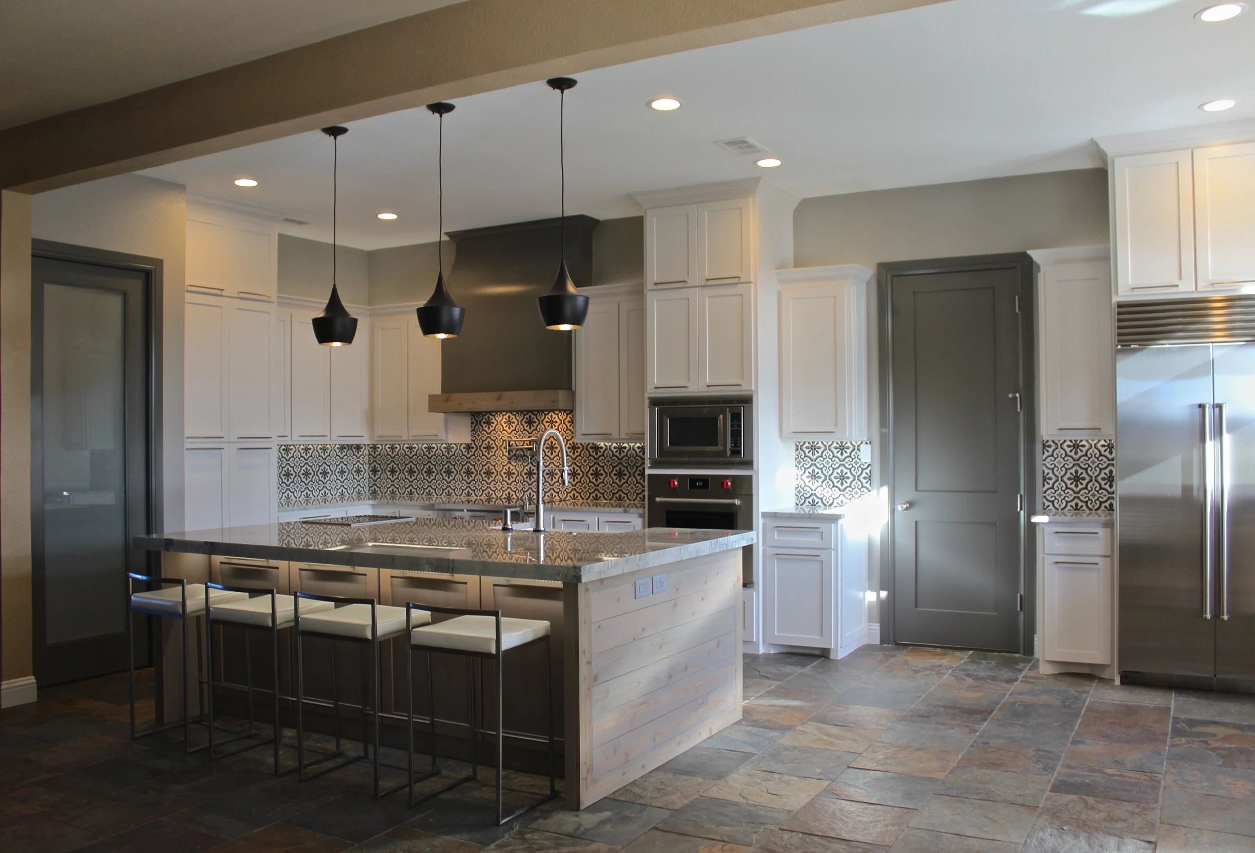I was able to refinish the original range hood. I opened up the space and installed a large Subzero refrigerator on the other side of the kitchen so that all of the space could be utilized. I incorperated a café door on the left side of the kitchen to conceal the utility area. 