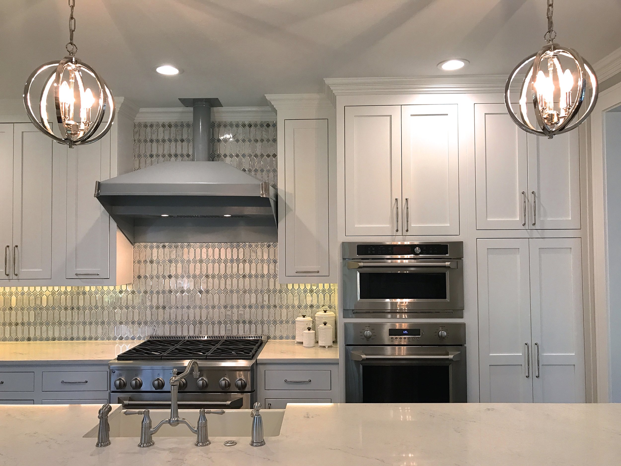 I always incorporate pendant lights over kitchen islands. This anchors the island and softens the angles a bit. 