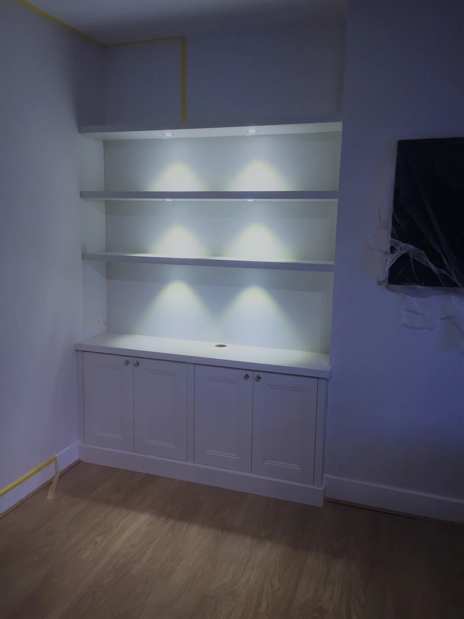 Fitted floating shelving with down lighting. Cabling is cleverly hidden behind the false panels in between each shelf.