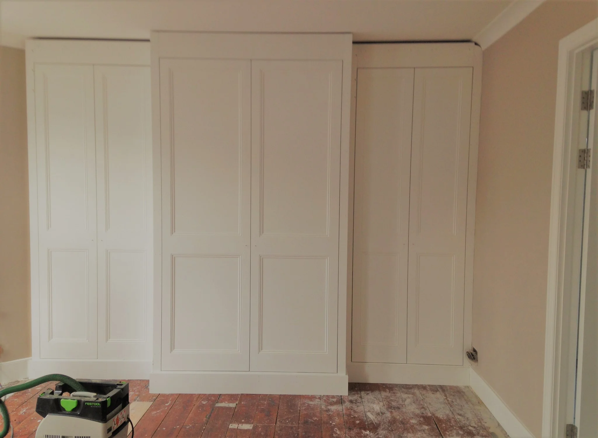 A classic six door wardrobe. The central wardrobe stepped in front of an existing fireplace to create more space and a grander looking finish.