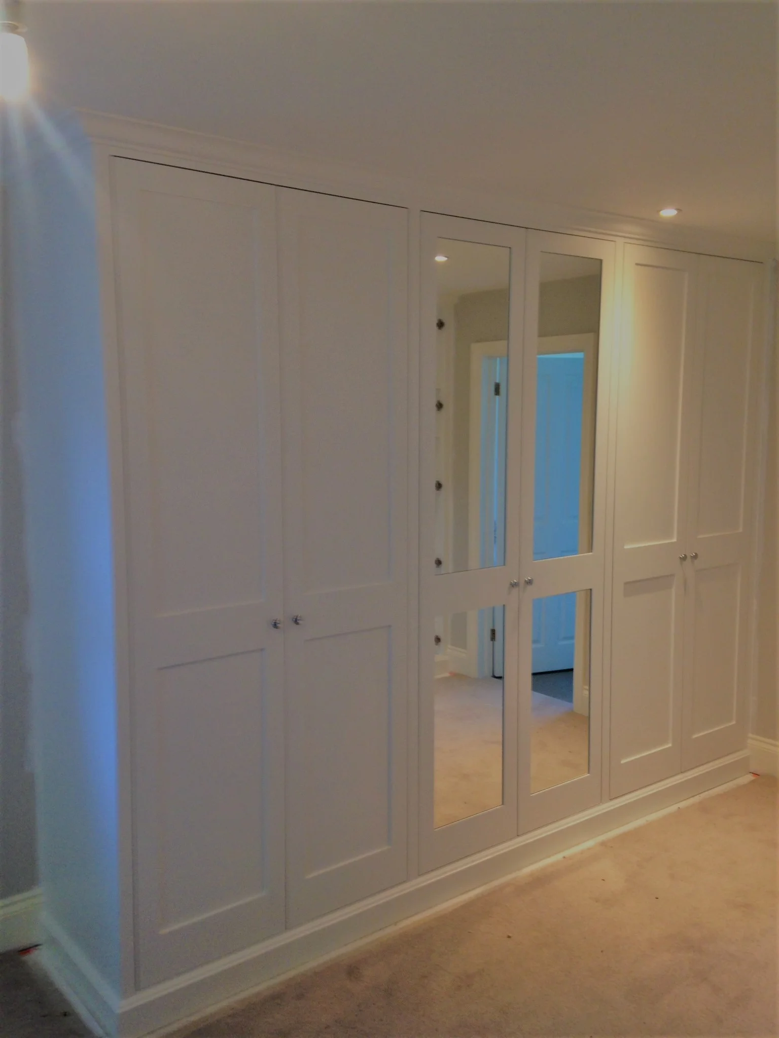A 6 door wardrobe with a central pair of mirrored panel doors.