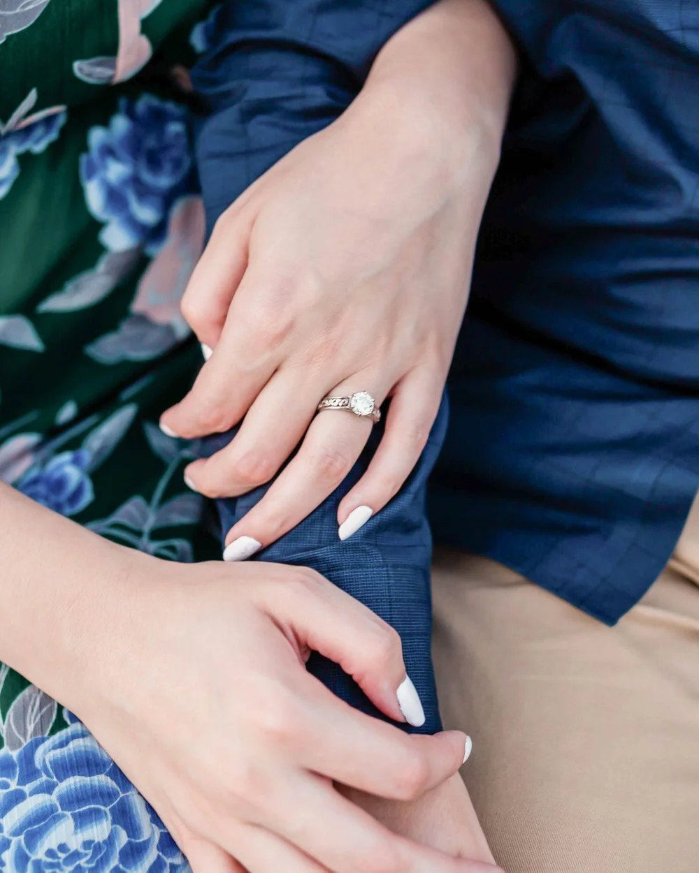 Arms of a male and female couple crossed showing the female's engagement ring