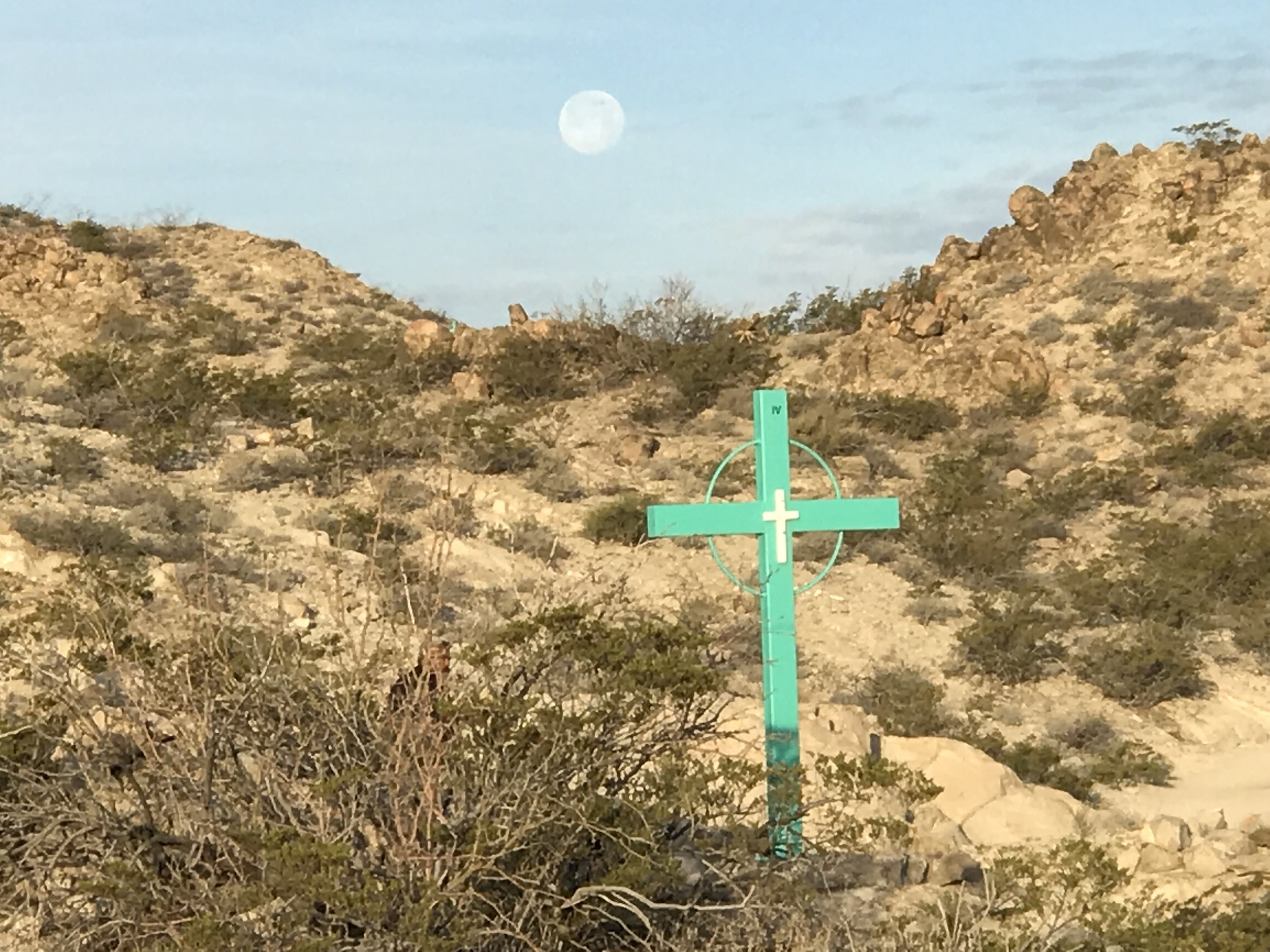  A full moon sets behind a cross marking the path up Christo Rey Mountain just outside El Paso.      