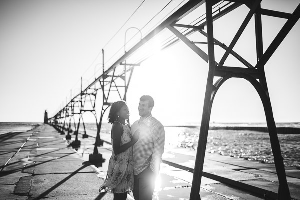 couple snuggling on pier at sunset in beautiful light, powerful connection, black and white 