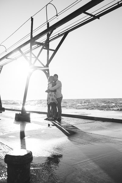 couple wrapped in each others arms on pier, black and white 