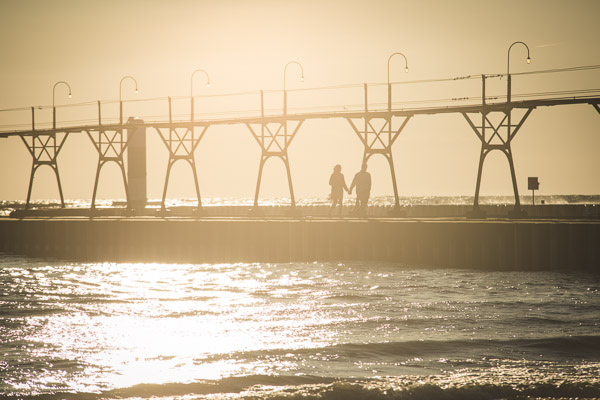 couple walking along golden pier, hand in hand, connected