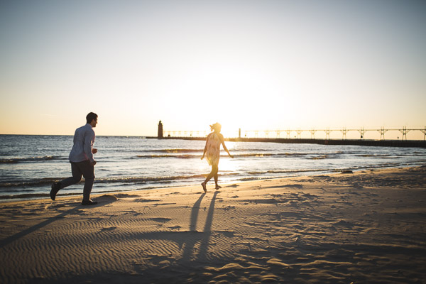 couple chasing each other along the beach in golden sunlight 