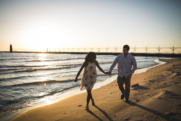 couple running along beach and in hand, golden light 