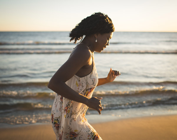 girl running along beachfront in golden light 