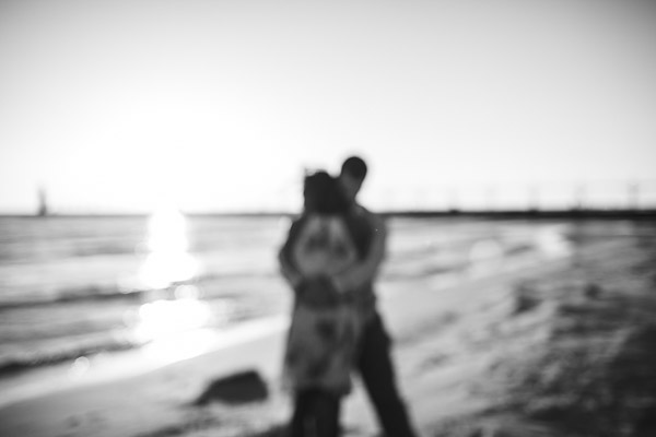 couple embracing on beach, out of focus, black and white, moody, intimate