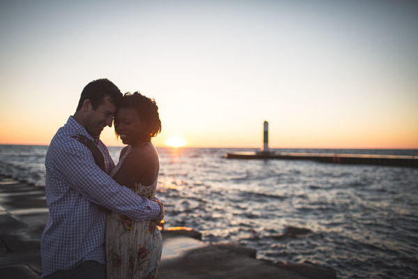 couple touching foreheads on beach with golden sun setting behind 