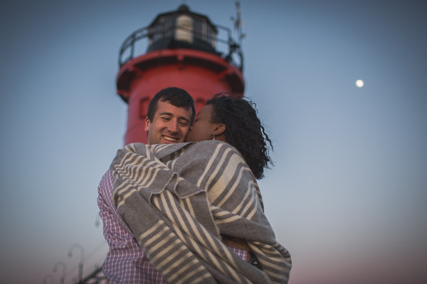 intimate embrace, loving kiss on pier in front of lighthouse with moon shining behind 