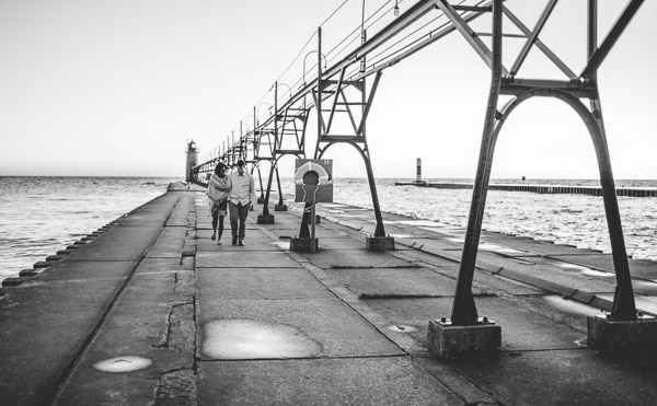 couple walking along pier, hand in hand, connection, movement, black and white 