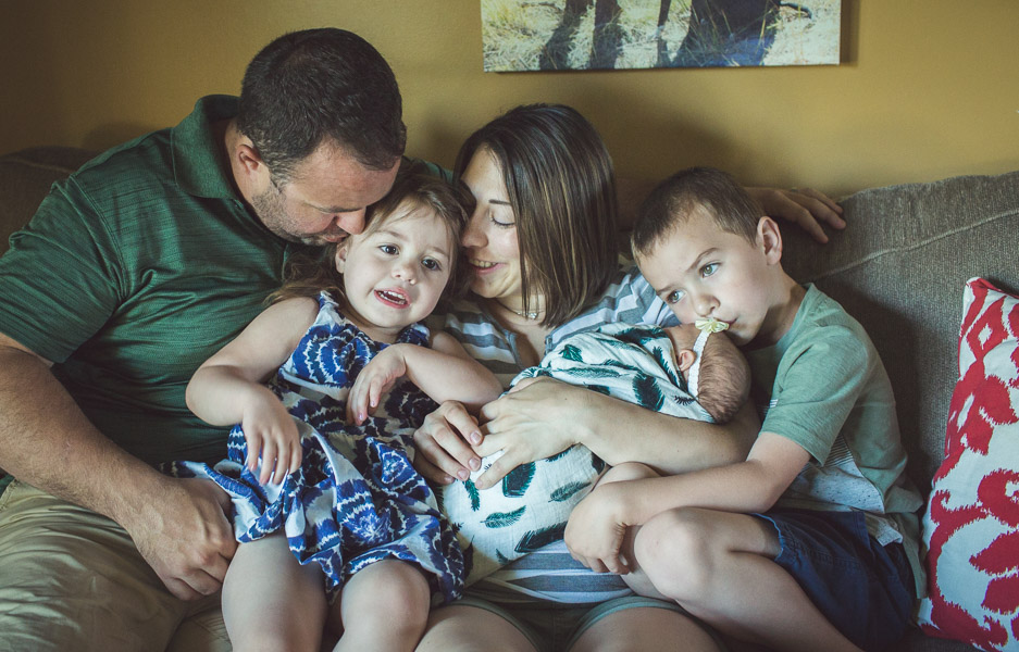 Family snuggles on couch in morning light 