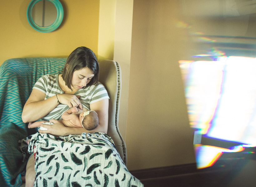mother nursing her newborn child in soft window light of prism