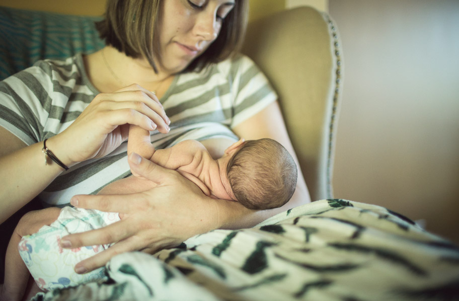 details; mother holding newborn child hand during nursing 