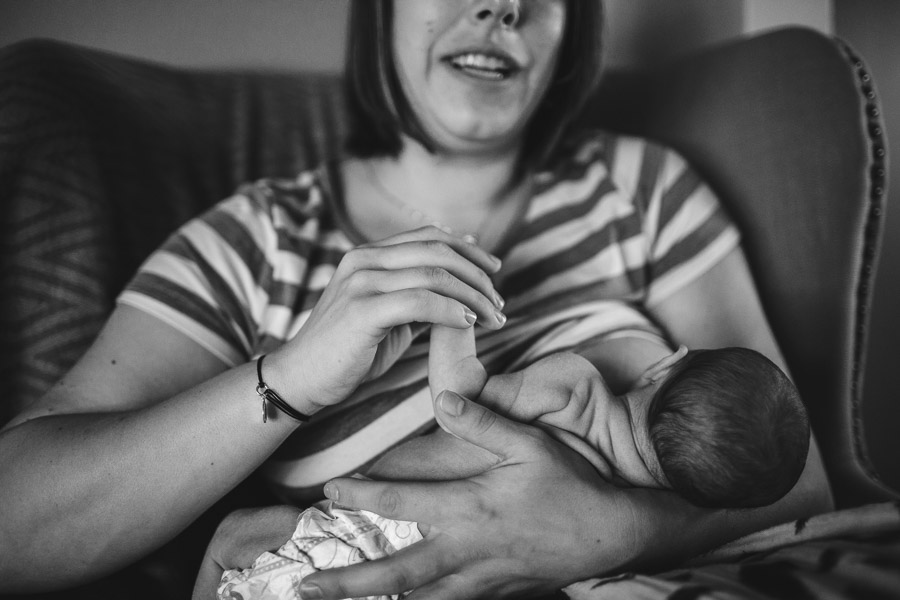 details, front angle portrait of mother nursing child while holding her hand 