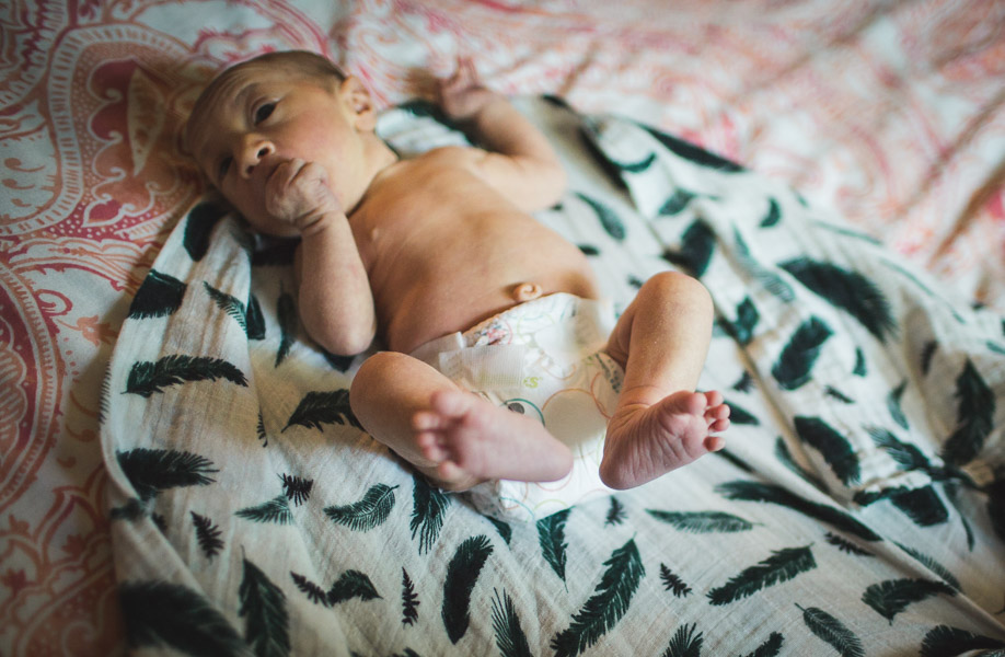 newborn baby lying on bed in soft window light 